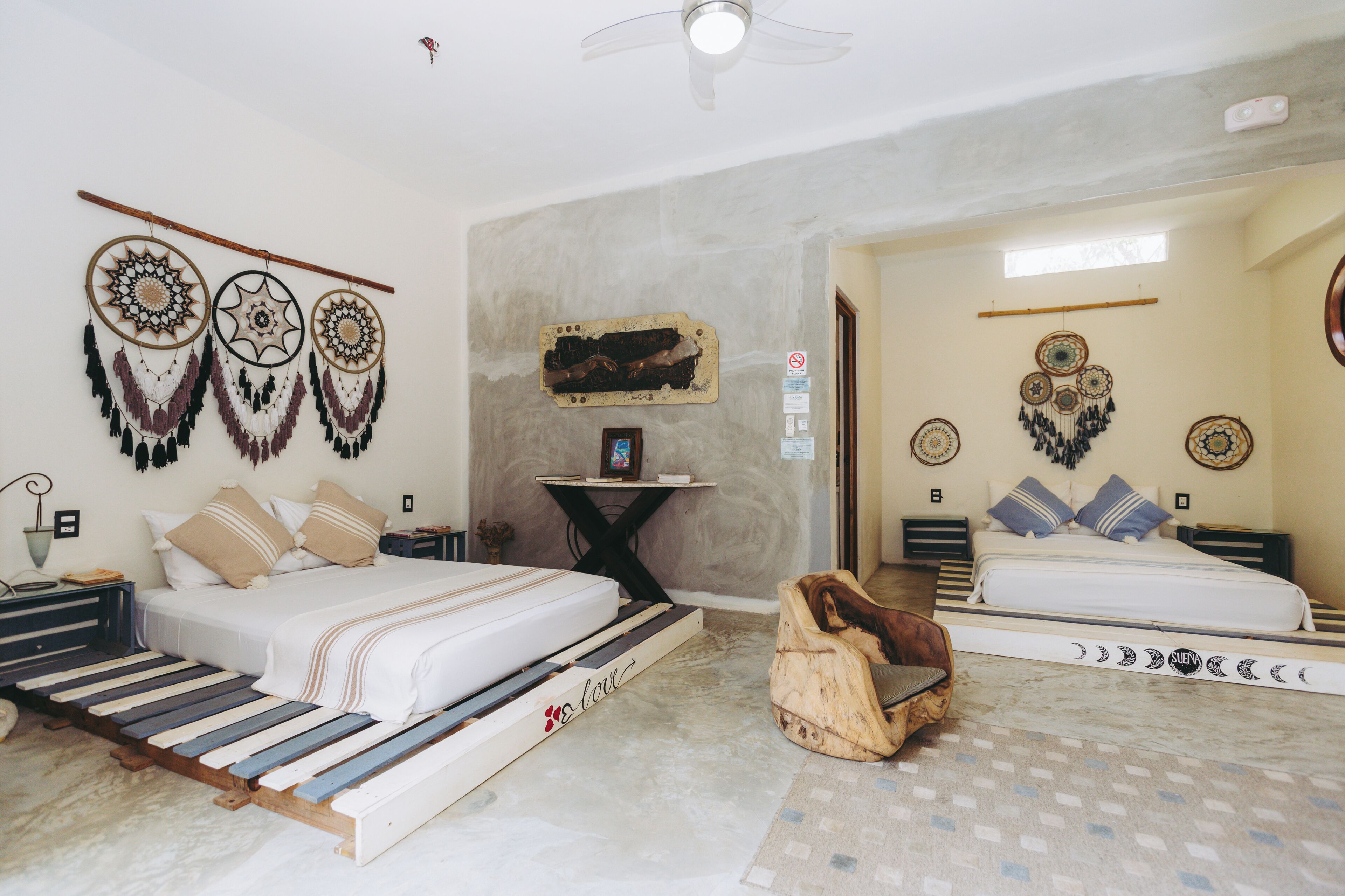 Quarto com duas camas, uma mesinha e decorações nas paredes.