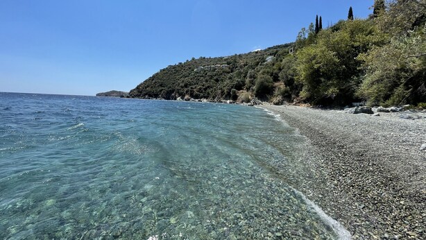 A pebble beach with clear water and a forested hillside. - Villa Achilles (Pera Melana)