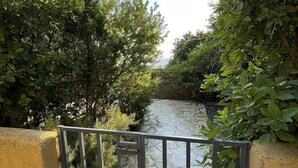 A stone pathway leading through a lush green area with a metal gate. - Villa Achilles (Pera Melana)
