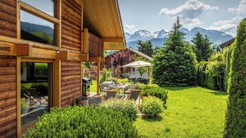 Une cabane en bois dotée d’une terrasse, de meubles de jardin et offrant une vue sur les montagnes.