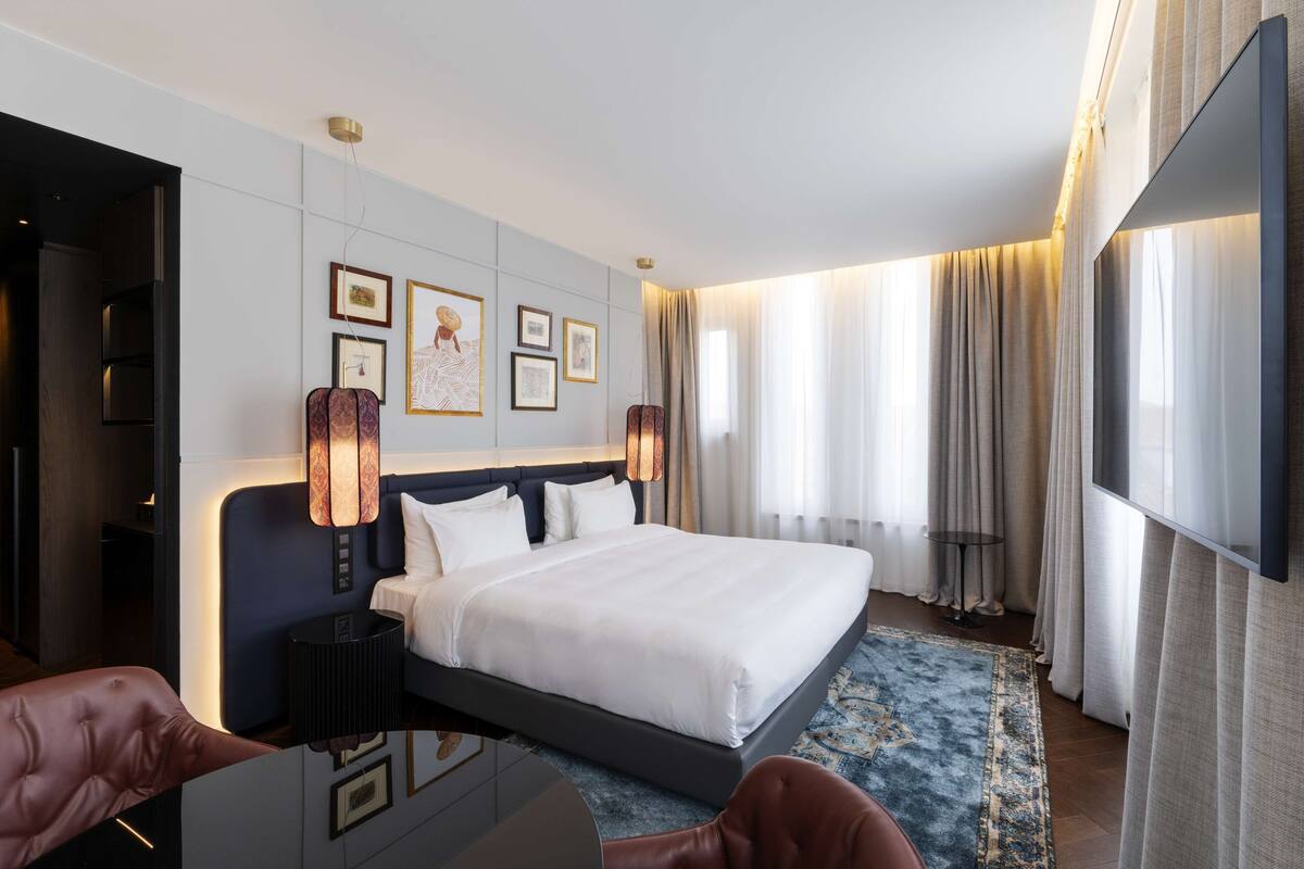 A modern hotel room with a large bed, a desk, and a TV.