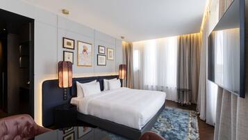 A modern hotel room with a large bed, a desk, and a TV.