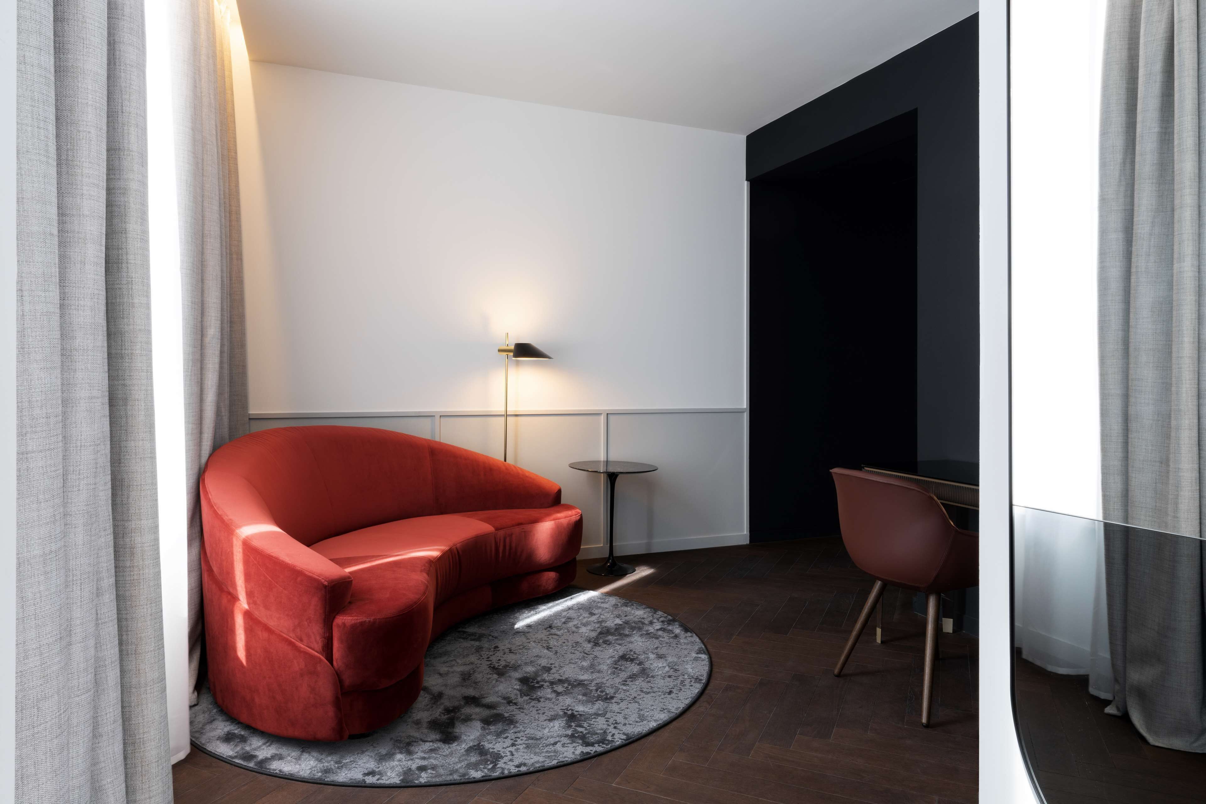 Una habitación moderna con un sofá rojo, una alfombra redonda, una mesita y una lámpara.