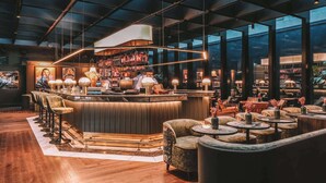 A modern bar area with a bar counter, seating, and a bartender. - Radisson Collection Hotel, Santa Sofia Milan (Milan)