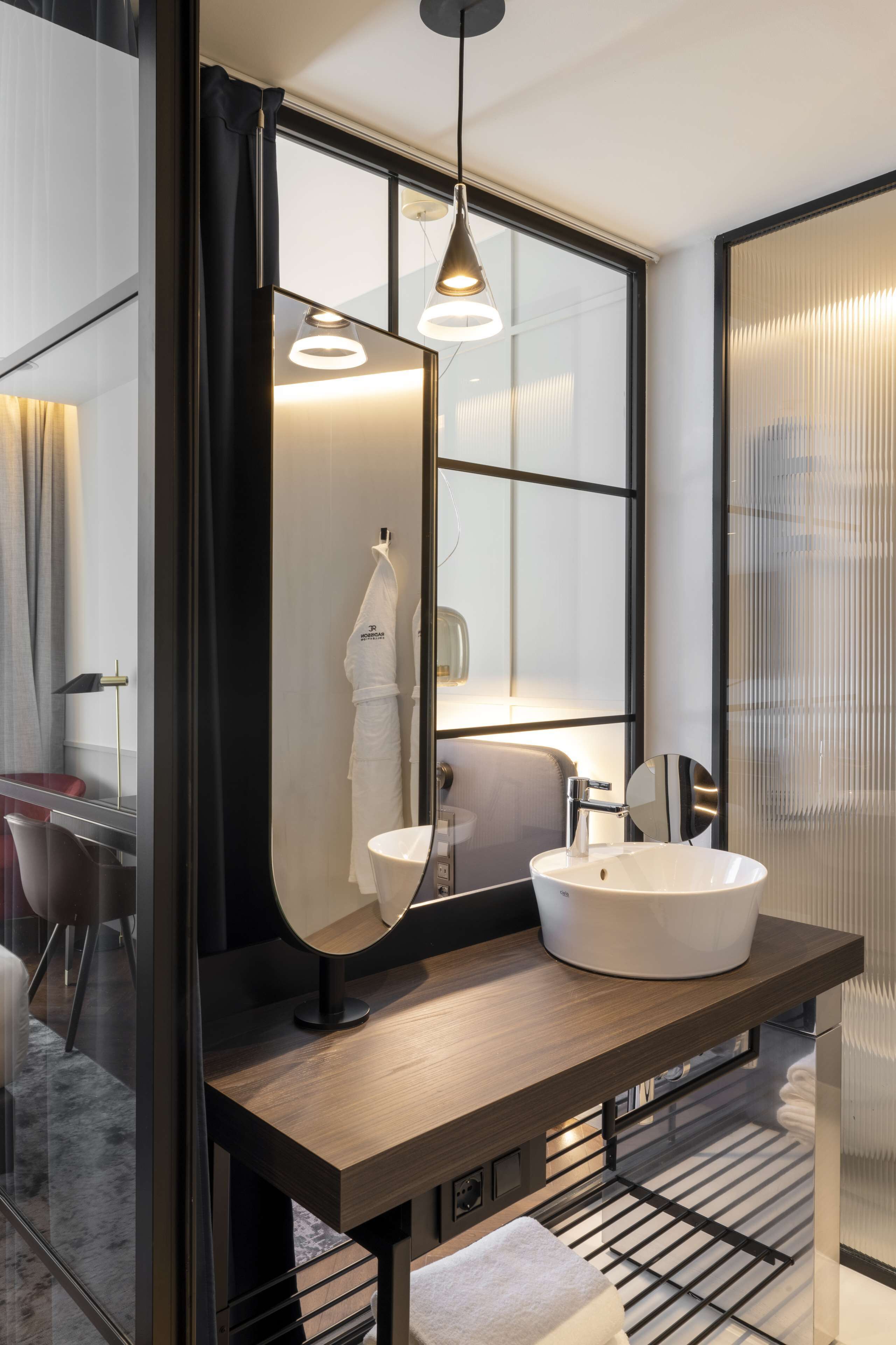 Un bagno moderno con un grande specchio, un lavabo rotondo e un portasciugamani.