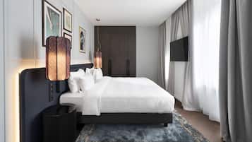 Una habitación de hotel moderna con una cama grande, un televisor de pantalla plana, una lámpara decorativa y una alfombra estampada.