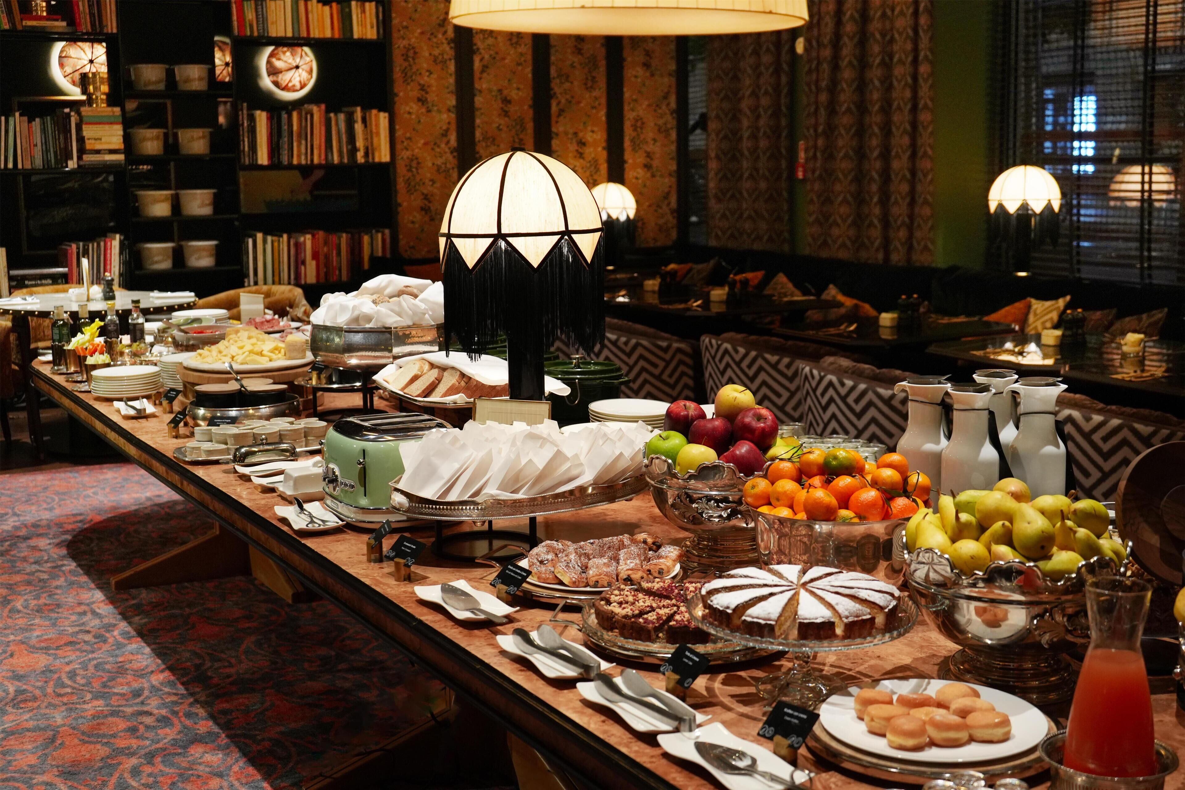 Un tavolo da buffet con diversi cibi e un'area salotto con divano e lampade.