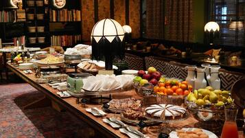 Un tavolo da buffet con diversi cibi e un'area salotto con divano e lampade.