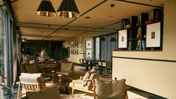 A spacious lobby with a high ceiling, multiple seating areas, and a large window providing natural light.