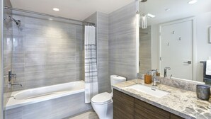 Une salle de bain moderne avec une douche en verre, des toilettes blanches et un meuble-lavabo en marbre avec un évier et un miroir.