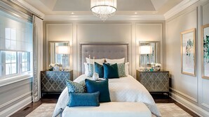 Une chambre spacieuse avec un grand lit, deux tables de chevet, un banc et un lustre.