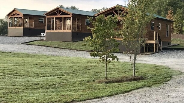 A row of cabins with a covered porch and a gravel driveway.