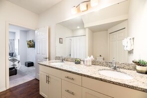 A modern bathroom with a large mirror, two sinks, and a shower. - Cozy Townhome Near Disney Parks (Kissimmee)