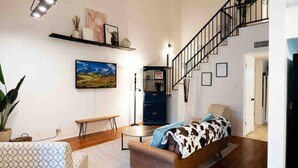 A living room with a sofa, a bench, a coffee table, a staircase, and a bookshelf. - Ranch Glam Townhome with Indoor Fireplace (El Paso)
