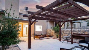 A covered patio area with stone walls, outdoor furniture, and a pergola structure. - Ranch Glam Townhome with Indoor Fireplace (El Paso)