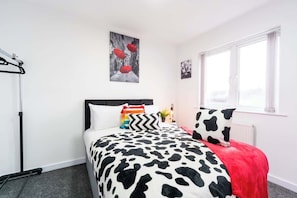 Une chambre à coucher comprenant un lit, un radiateur, une fenêtre et une œuvre d’art accrochée au mur.