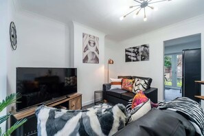 Ein modernes Wohnzimmer mit Flachbildfernseher, einer Couch mit gemusterten Kissen und einem Wanddekor.