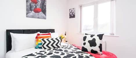 Un dormitorio con cama, ventana y una obra de arte colgada en la pared.