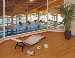 A sunlit room with a pool view, a lounge chair, a potted plant, and a teapot. - Boavista Golf Resort Apartment (Lagos)