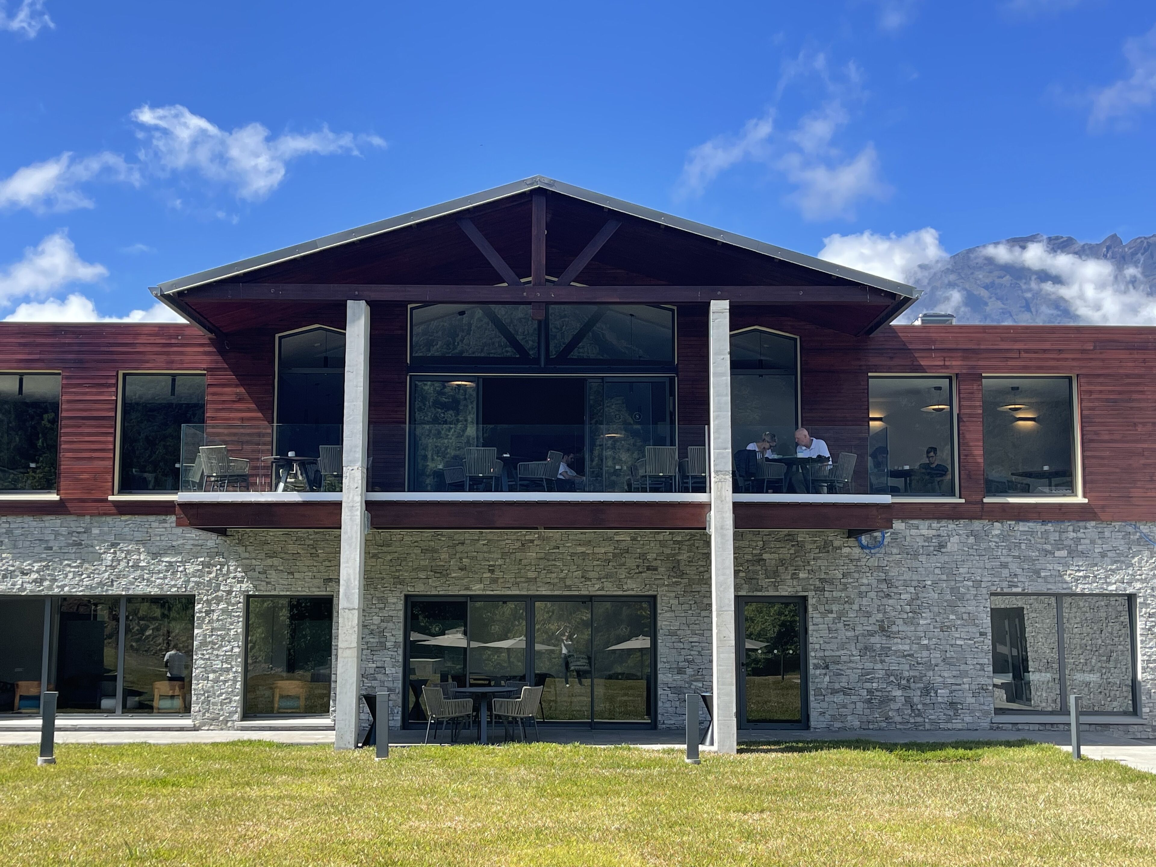Un bâtiment moderne avec une façade en pierre, de grandes fenêtres et un toit plat.