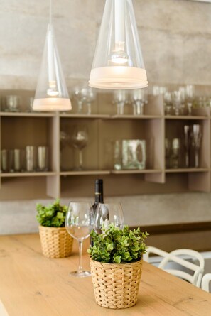 A wooden table with woven baskets containing green plants and wine glasses, under pendant lights. - Casa Lago - Varandas do Lago (Loulé)