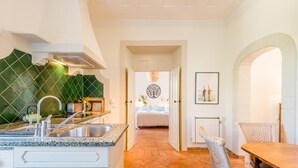 A kitchen with a granite countertop, white cabinetry, and a green tiled backsplash. There is a dining area with wicker chairs and a wooden table. - Casa Omlandia With Pool - Lagos Old Town (Lagos)