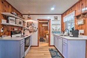 A kitchen with wooden walls, a stove, and cabinets. There is a sign on the wall and a window with blinds. - Cozy Knoxville Getaway ~ 8 Mi to Downtown! (Knoxville)