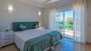 A bedroom with a large bed, two bedside tables, a nightstand, and a view of a balcony. - Boavista Resort - Casa Belinda (Lagos)