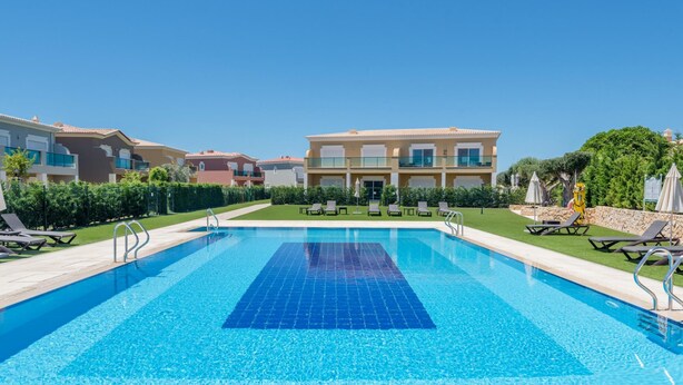 A swimming pool with lounge chairs, a clear blue sky, and a building in the background. - Boavista Resort - Casa Belinda (Lagos)