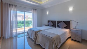 A hotel room with two beds, a nightstand, a lamp, and a view of greenery outside. - Boavista Resort - Casa Belinda (Lagos)