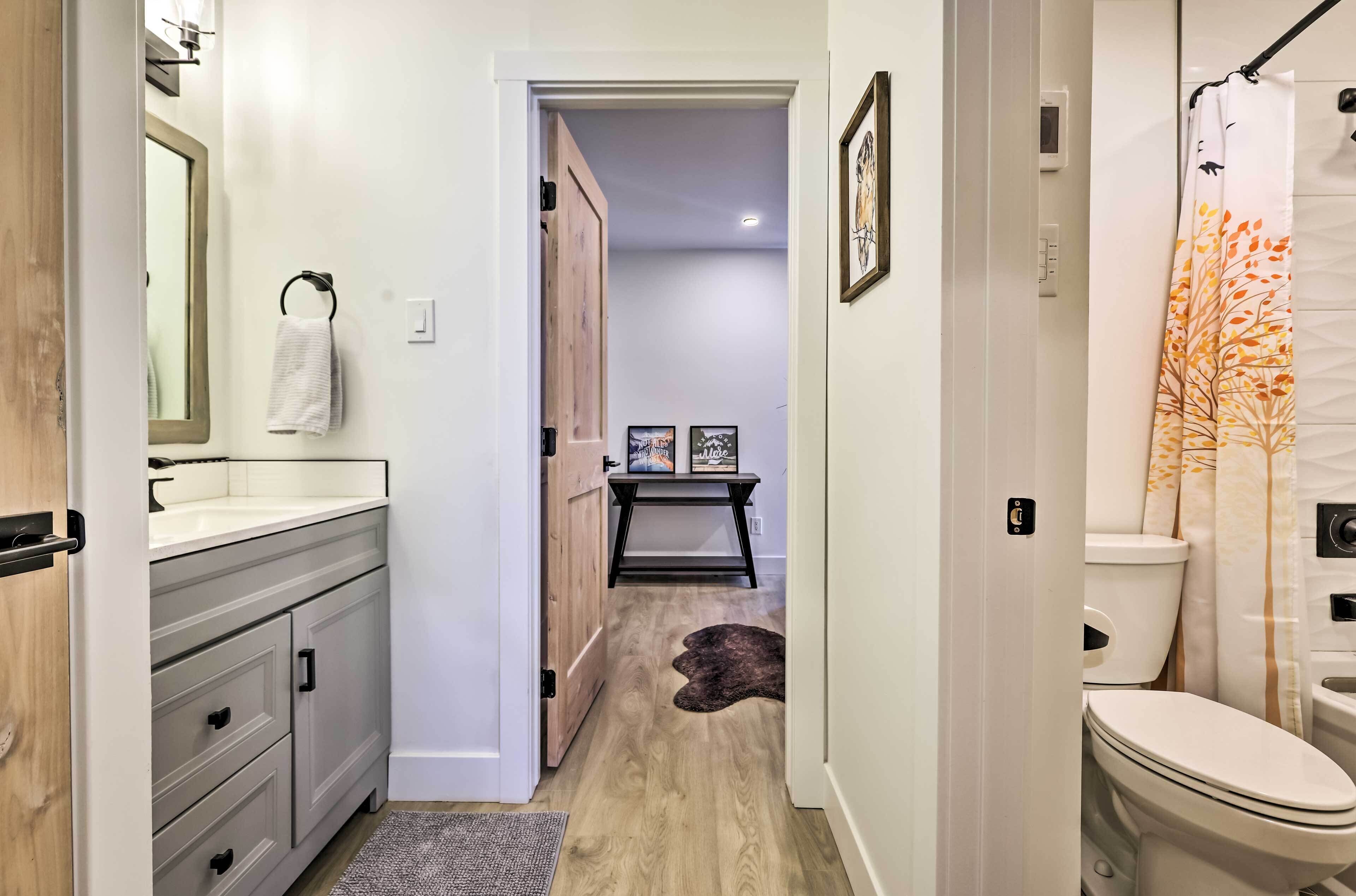 A modern bathroom with a shower curtain, a toilet, and a sink area.