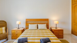 Una habitación de hotel con una cama grande, dos mesitas de noche, una silla y un armario.