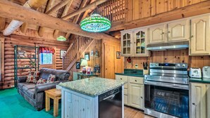 Ein Holzhaus-Interieur mit einer Küchenzeile, inklusive Geschirrspüler, Backofen und Schränken.