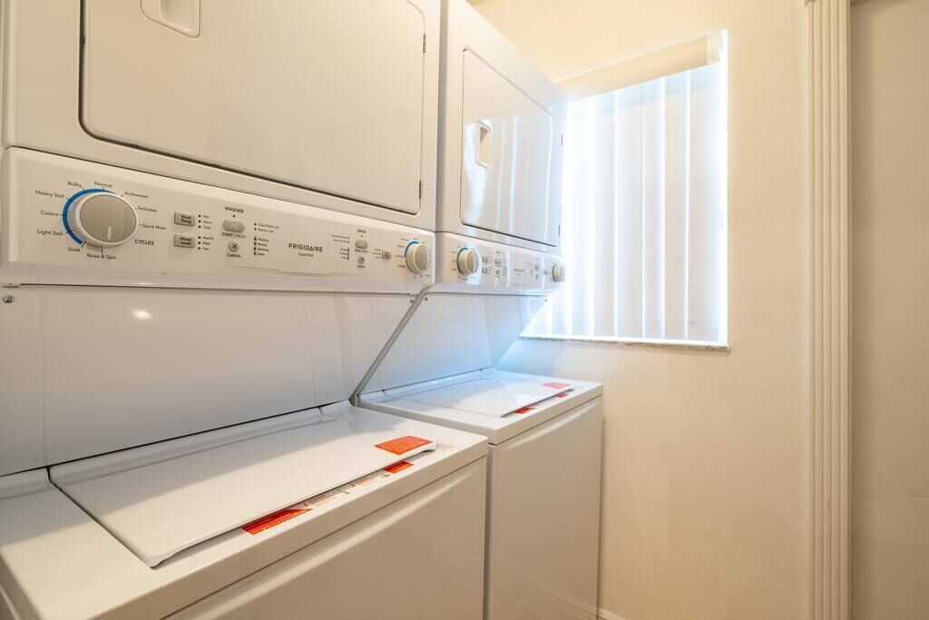 A front-loading washer and dryer unit with control knobs and a paper towel dispenser.