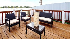 A wooden deck with wicker furniture and a glass-top table. - Stunning Lake-Front Villa with Pool & Spa (Pembroke Pines)