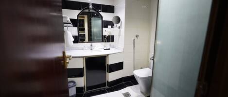 A bathroom with a white sink, black and white tiled walls, a mirror, and a toilet.