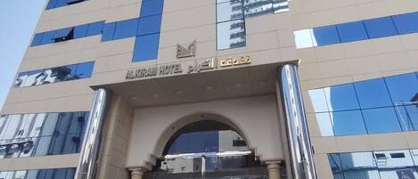 A tall hotel with a modern facade, featuring a prominent entrance with a glass door and a sign above it.