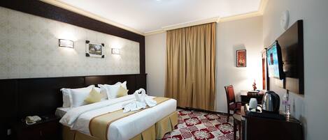 Une chambre d’hôtel dotée d’un grand lit, d’un bureau avec une chaise, d’un téléviseur à écran plat, d’un téléphone et d’un panneau décoratif mural.