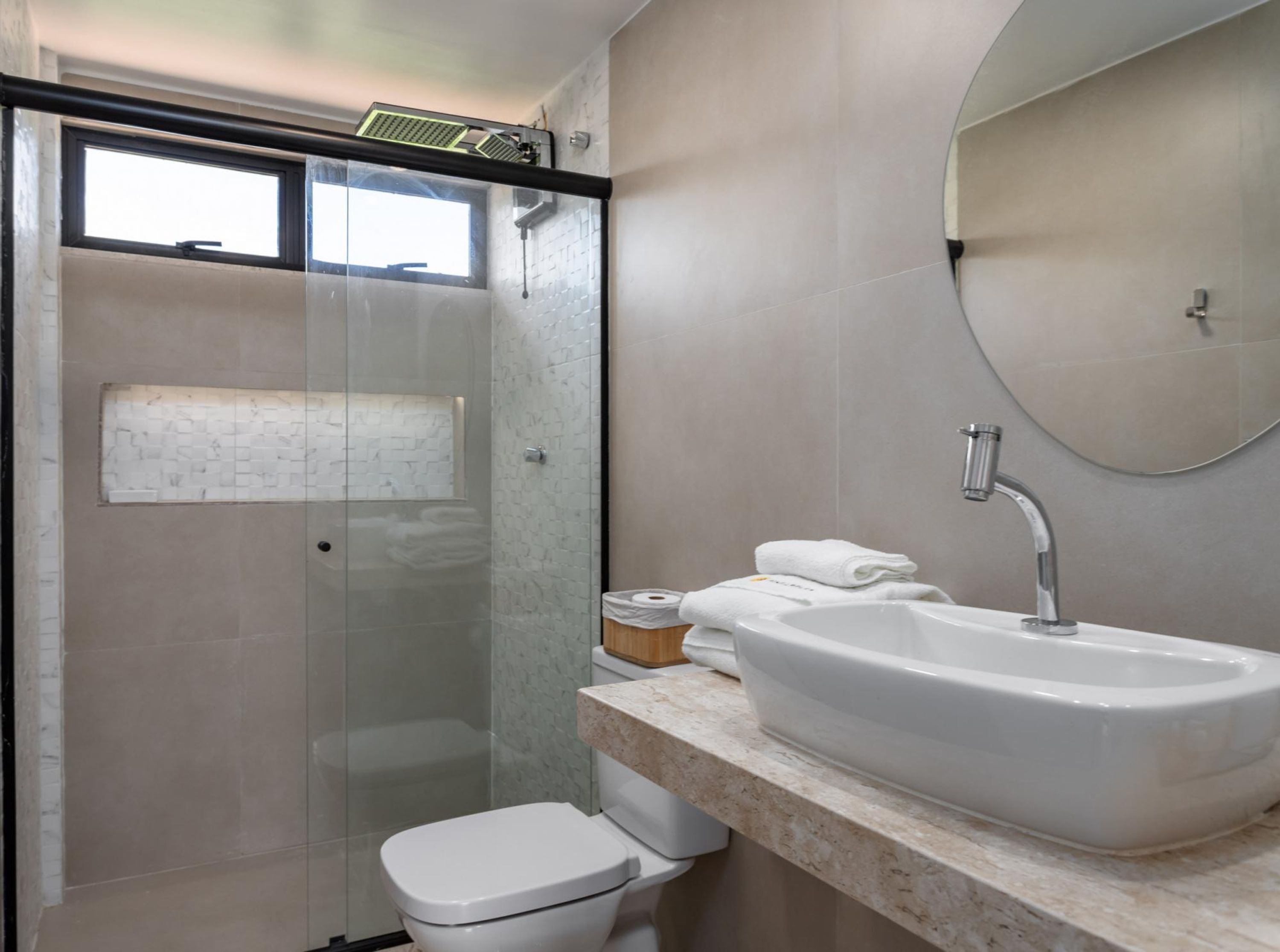 A modern bathroom with a glass shower enclosure, a white sink, and a toilet.