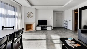 A modern living room with a fireplace, a flat-screen TV, and a dining area with a table and chairs. - Falesia Beach B in Albufeira (Albufeira)