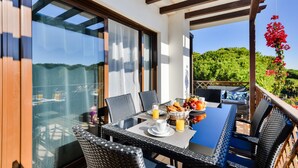 An outdoor dining area with a table set for breakfast, including bread, fruit, and juice. - Falesia Beach B in Albufeira (Albufeira)