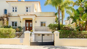 Una casa de dos pisos con techo de tejas, puerta principal y entrada protegida por una reja.