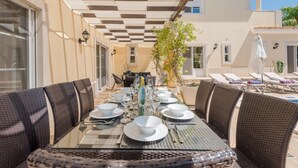 Un comedor con techo a cuadros, asientos al aire libre y vista a un edificio al fondo.