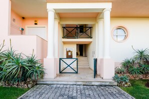 A building entrance with a double door, a small balcony, and a circular window. - Quinta do Paiva - Jardins do Vale (Albufeira)