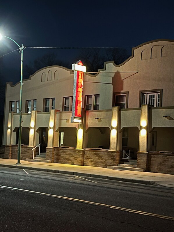 A hotel with a prominent 'HOTEL' sign, a brick facade, and multiple windows.