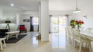 A spacious living room with a dining area, large windows, and a view of the outdoors. - Amazing Apartment in Albufeira (Albufeira)