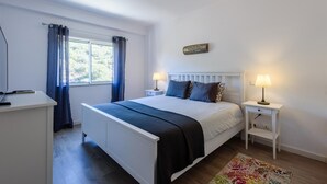 A bedroom with a bed, bedside tables, a desk, and a window with curtains. - Amazing Apartment in Albufeira (Albufeira)