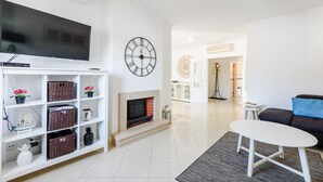 A modern living room with a flat-screen TV, a fireplace, a clock, and a sofa. - Amazing Apartment in Albufeira (Albufeira)