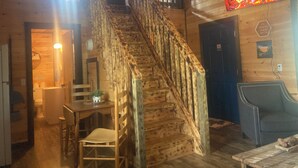 Un intérieur en bois avec un escalier, un coin repas et une cheminée.