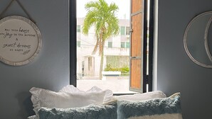 Un dormitorio con cama, almohadas, una ventana y un adorno en la pared.